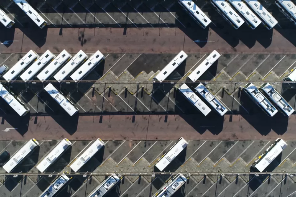 Aerial view from directly overhead of buses parked in large asphalt lot